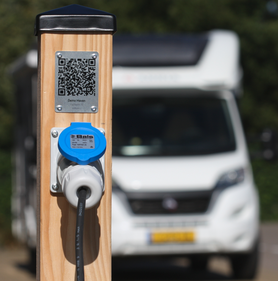 Camper bij een elektriciteit aansluitpunt met QR code